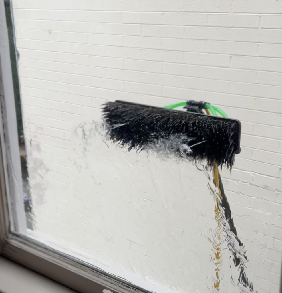 Water-fed pole brush cleaning a window